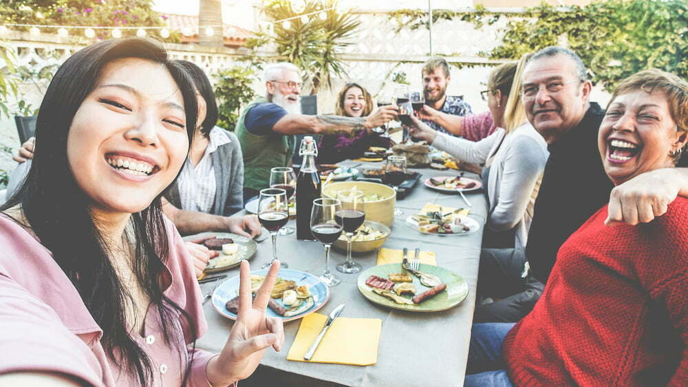 Happy family and friends taking selfie at barbecue dinner - people having fun eating and drinking on patio house outdoor